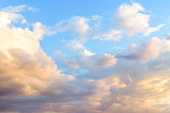 An expansive view of soft clouds in a vibrant sunset sky, showcasing warm and pastel tones. HD wallpaper