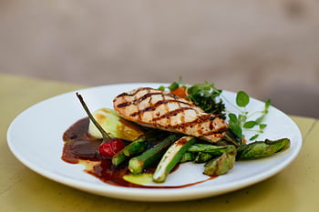 Savor a delicious grilled chicken breast paired with fresh vegetables, elegantly plated. HD wallpaper