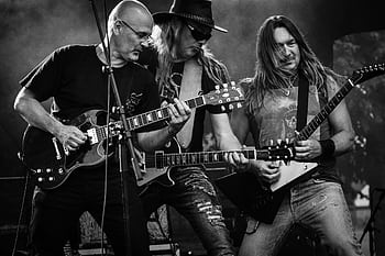 Black and white of a rock band passionately performing on stage with guitars. HD wallpaper