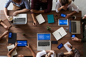 Overhead view of a diverse team in a business meeting using laptops and tablets. HD wallpaper