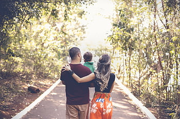 A family enjoying a leisurely walk on a sunny park trail, showcasing togetherness and love. HD wallpaper
