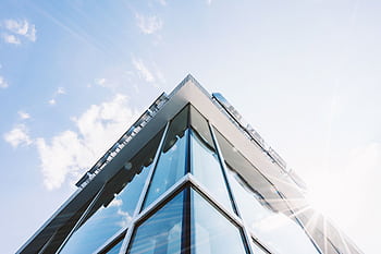 Low angle shot of a modern glass building with sun glare reflecting on its surface. HD wallpaper