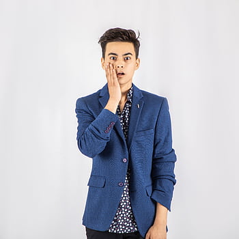 A young man expressing surprise while posing in a blue blazer against a white background. HD phone wallpaper