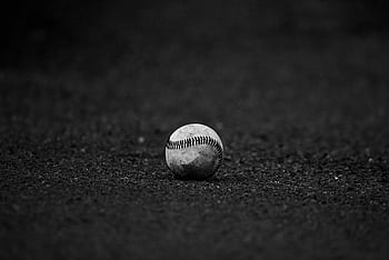 A monochrome of a baseball resting on a textured dark surface, perfect for sports themes. HD wallpaper