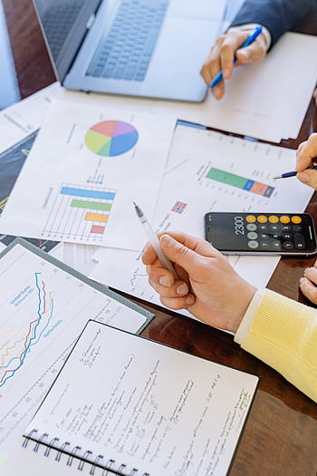 A close-up of businesspeople analyzing financial data and charts during a meeting. HD phone wallpaper