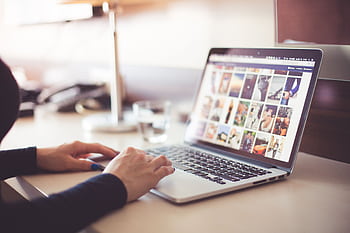 Close-up of hands typing on a laptop with an gallery open on the screen. HD wallpaper