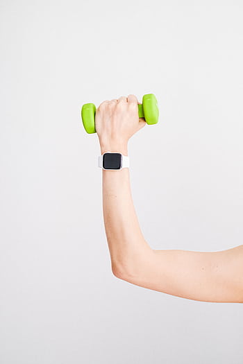 Arm holding a green dumbbell with a smartwatch on wrist against a white background. HD phone wallpaper