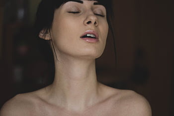 Close-up of a serene young woman with eyes closed, enjoying a moment of tranquility indoors. HD wallpaper