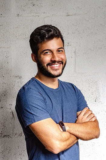 Portrait of a happy man with arms crossed, exuding confidence and friendliness. HD phone wallpaper