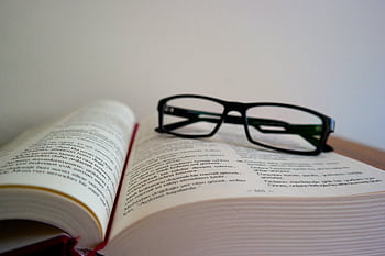 An open book with eyeglasses resting on top, symbolizing learning and education. HD wallpaper