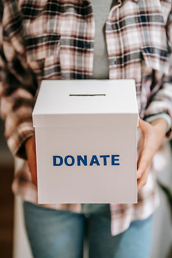 Close-up of a person holding a 'donate' box, encouraging charity and support. HD phone wallpaper