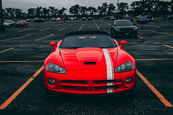 Vibrant red sports car parked in an empty lot with overcast skies. HD wallpaper
