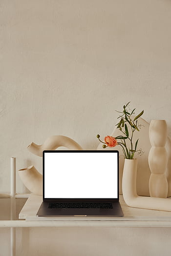 Stylish modern workspace featuring a minimalist design with decorative vases, a green plant, and a blank laptop screen. HD phone wallpaper