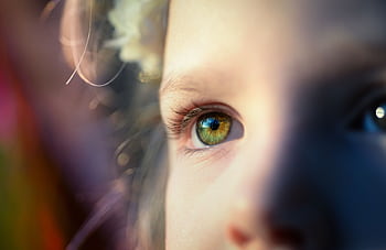 A close-up of a child's eye captures innocence and beauty, enhanced by soft, dreamy light. HD wallpaper