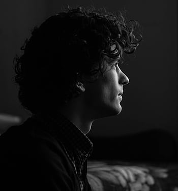 Side profile of a young man with curly hair in moody lighting. HD phone wallpaper