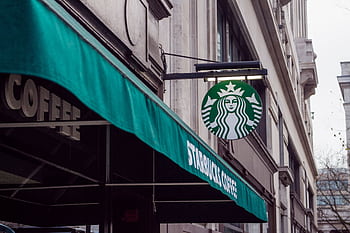 Exterior view of a Starbucks coffee shop in a city setting, featuring signage and awning. HD wallpaper