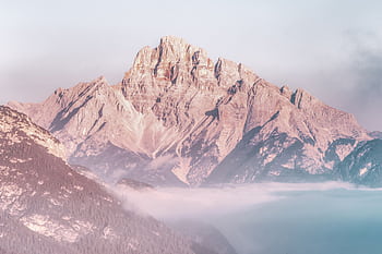 Stunning view of a sunlit mountain peak rising above the morning fog, creating a serene and majestic landscape. HD wallpaper