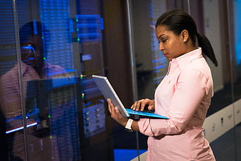 A focused software engineer working on a laptop in a server room, reflecting dedication in tech. HD wallpaper