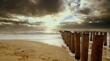 row of wooden pylons on a beach, sea, wood, clouds, pylons, beach HD wallpaper