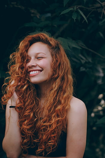 A candid portrait of a joyful woman with curly red hair, expressing natural beauty and happiness. HD phone wallpaper