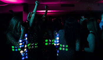 Energetic nightclub scene with people dancing under colorful neon lights. Perfect for nightlife themes. HD wallpaper