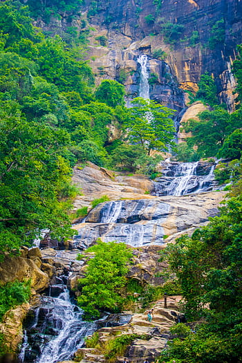 A breathtaking view of a cascading waterfall surrounded by lush greenery, perfect for nature enthusiasts. HD phone wallpaper