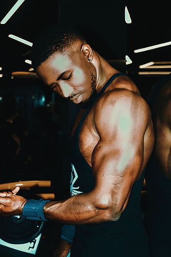Black man demonstrating muscular physique in gym, highlighting strength and fitness. HD phone wallpaper