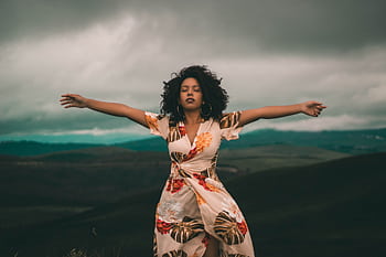 A woman in a flowing dress enjoys peaceful moments in a vast, cloudy landscape. HD wallpaper