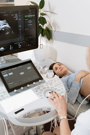 Pregnant woman undergoes ultrasound scan by medical professional in hospital room. HD phone wallpaper