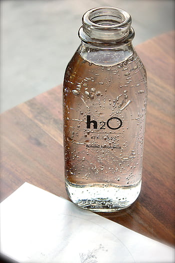 Close-up of a sparkling water bottle on a wooden table, refreshing and hydrating. HD phone wallpaper