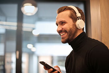 Bearded man smiling with heads and smart indoors, enjoying music. HD wallpaper
