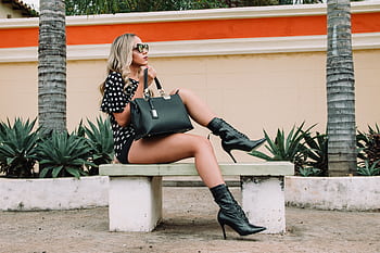 Fashionable woman in boots and sunglasses poses on a bench outdoors. HD wallpaper