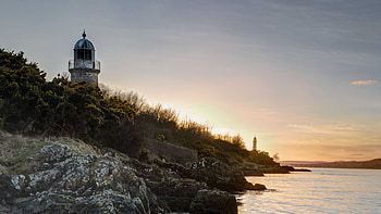 Stones Rocks Green Trees Bushes Slope River Lighthouse Blue Sky During Sunset Nature HD wallpaper