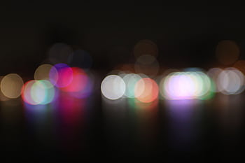 Vibrant and colorful bokeh lights defocused against a dark night background, creating an abstract visual. HD wallpaper