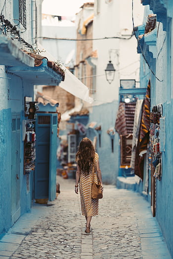 A woman wanders through the vibrant blue alleyways of Chefchaouen, Morocco. HD phone wallpaper