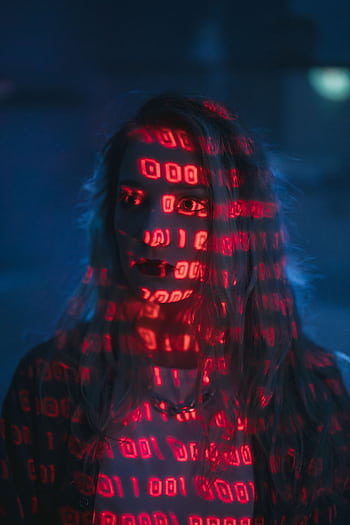 A woman with red binary code projected on her face, signifying technology and cybersecurity. HD phone wallpaper