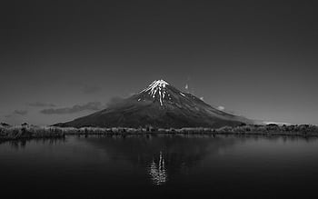 Breathtaking black and white view of Mount Taranaki with a tranquil lake reflection, New Zealand. HD wallpaper