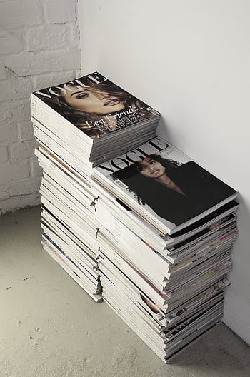 A stack of fashion magazines neatly arranged against a white brick wall, showcasing style and elegance. HD phone wallpaper
