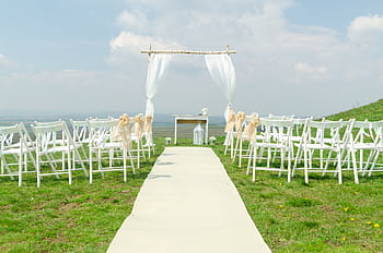 Elegant outdoor wedding setup with chairs and arch under a blue sky. HD wallpaper