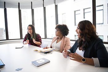 Three businesswomen engaging in a productive meeting inside a modern office space. HD wallpaper