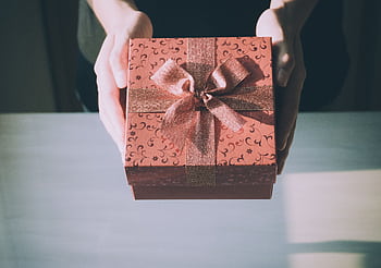 Hands presenting a beautifully wrapped gift box with a floral pattern, perfect for any celebration. HD wallpaper