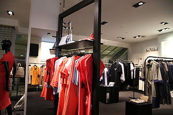 Discover a chic fashion boutique showcasing a variety of colorful clothes on elegant racks. HD wallpaper