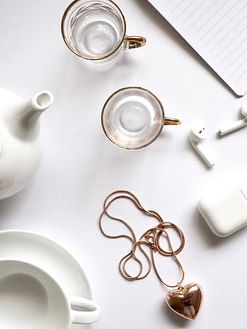 Minimalist flat lay featuring gold jewelry, glass cups, and a white tea set, perfect for luxury lifestyle themes. HD phone wallpaper
