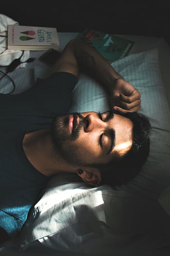 A serene portrait of a young man sleeping peacefully in a sunlit bedroom setting. HD phone wallpaper