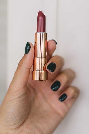 Close-up of a hand with dark polished nails holding a stylish lipstick tube against a neutral background. HD phone wallpaper