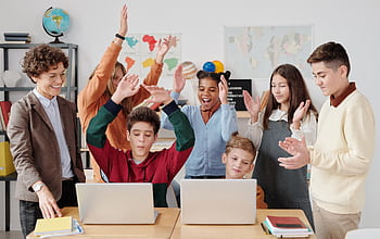 A group of happy students and a teacher clapping together in a school classroom. HD wallpaper