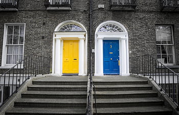A vivid yellow and blue doorway with steps leading up to a historic brick building facade. HD wallpaper