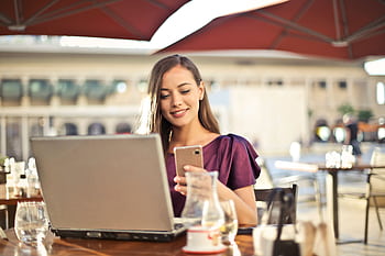 Woman enjoying remote work at a café, using a laptop and smart. HD wallpaper