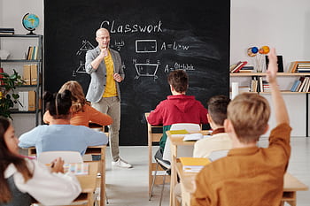 Teacher explaining geometry as students engage in a modern classroom setting. HD wallpaper