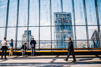 Business professionals in a modern office against a London skyline view. HD wallpaper